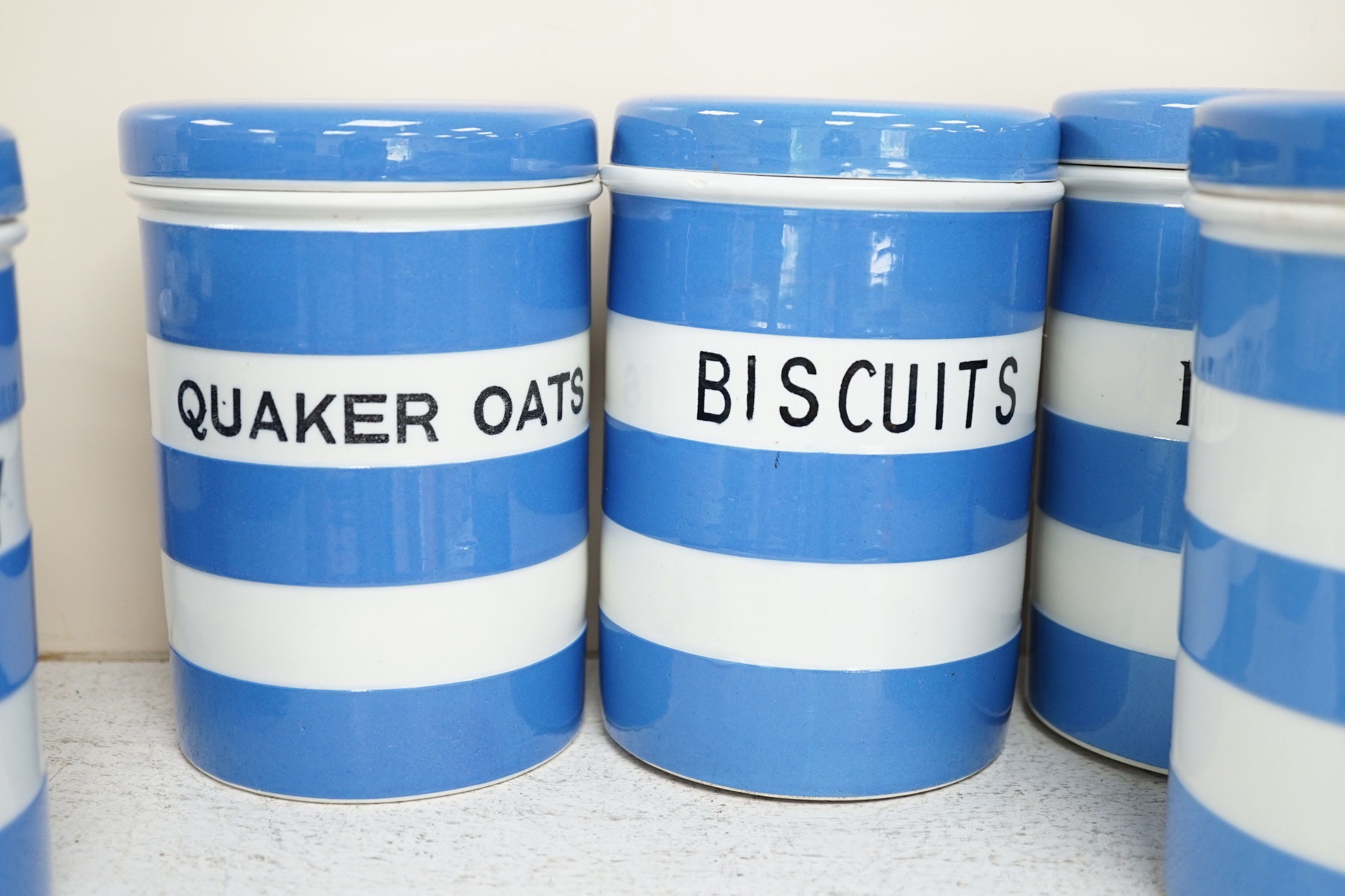 T.G.Green Cornish Kitchenware, eight 17cm lidded storage jars, comprising Currants, Caster Sugar, Granulated Sugar, Indian Tea, Macaroni, Biscuits, Pearl Barley and Quaker , Oats, Black Shield marks. Condition - fair to
